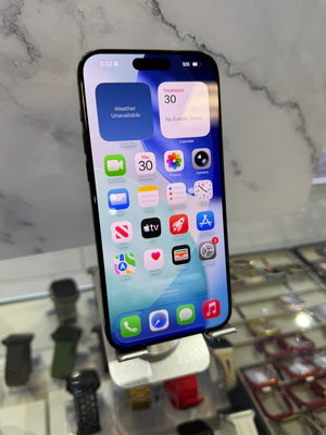 A black iPhone with a large screen displaying various colorful app icons, shown on a white display stand inside a retail store.