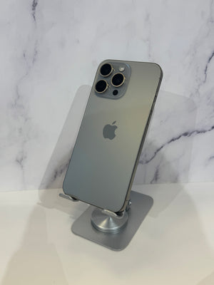 A gray Apple iPhone Pro shown from the back, resting on a silver metal stand against a white marble-patterned background.