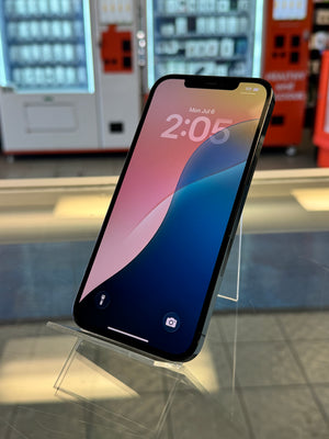 A black smartphone with a colorful pink, blue, and yellow wallpaper is displayed on a clear acrylic stand inside what appears to be a retail store or showroom.