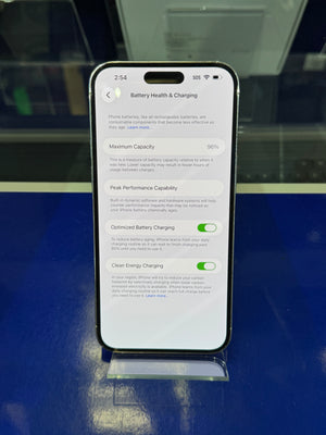 Smartphone displaying battery health and charging information on a reflective surface.