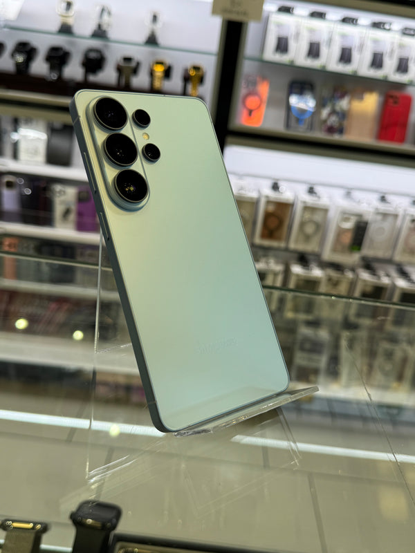 A mint green Samsung Galaxy Ultra smartphone shown from the back, resting on a clear acrylic display stand inside a retail store.