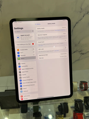 An iPad displaying the Settings app screen, photographed in a retail or showroom environment with a marble-patterned wall behind it.