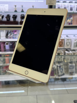 A gold-colored tablet smartphone with a black screen, resting on a clear display stand inside a retail store.
