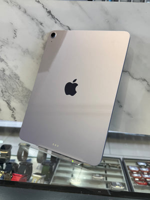 A silver Apple iPad shown from the back, resting on a white marble-patterned surface with a store interior visible in the background.