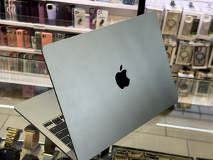 Silver Apple laptop on display in a store with various items in the background