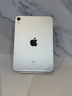 Silver Apple iPad back view standing upright on a clear display stand against a white marble-patterned background.