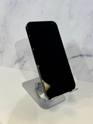 A black smartphone displayed upright on a silver metal stand against a white marble-patterned background.