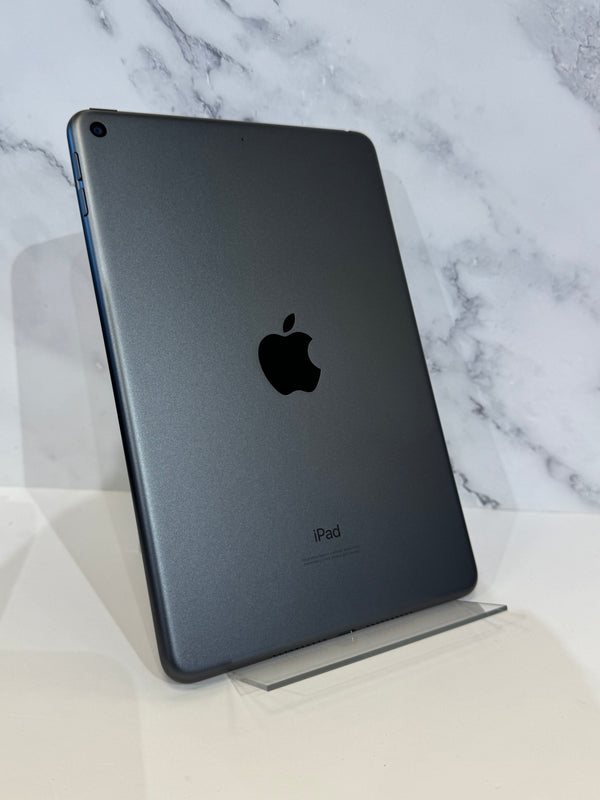 A dark gray Apple iPad shown from the back, standing upright on a clear acrylic display stand against a white marble-patterned background.