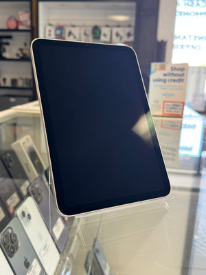 A black tablet with a silver bezel displayed on a clear stand inside a retail store.