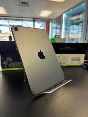 A silver Apple iPad shown from the back, resting on a display stand in a retail or showroom environment.