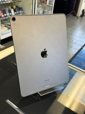 Back view of a silver Apple device with a black logo on a reflective surface.