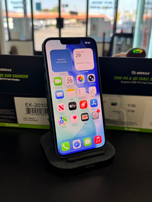 A black smartphone docked on a charging stand, with two Esouk electric car charger boxes visible in the background in front of a window.