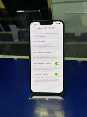 Smartphone displaying battery health and charging settings on a reflective surface