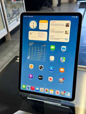 Tablet displaying a home screen with various apps on a stand.