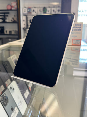A black tablet with a silver edge standing on a clear display stand inside a retail store.
