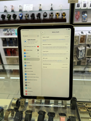 A tablet device with a black bezel displaying a settings interface, photographed in a retail store environment with watch displays visible in the blurred background.
