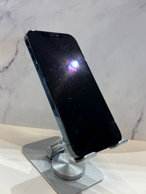 A black smartphone with a reflective screen stands on a silver metal adjustable display stand against a light marble-patterned background.