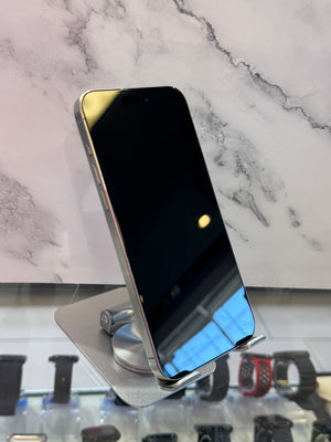 A silver smartphone with a black screen stands on a metallic display stand in front of a white marble-patterned background.