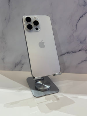 A silver Apple iPhone shown from the back, resting on a metallic stand against a light marble-patterned background.