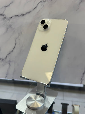 An Apple iPhone with a cream-colored back panel and silver trim, displayed on a metallic stand against a gray marble-patterned background.