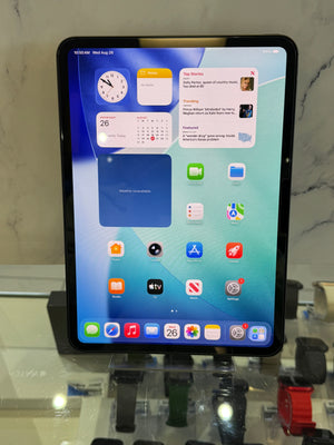 A black tablet with a colorful home screen displayed on a stand in a retail or showroom setting.