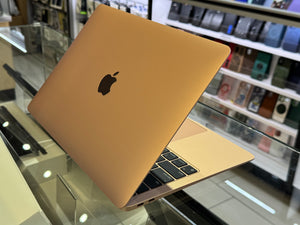 Gold laptop with Apple logo on a glass surface in a store setting