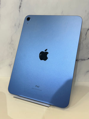 A blue Apple iPad shown from the back, resting on a small display stand against a light marble-patterned background.