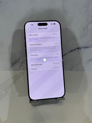 A black smartphone shown upright on a small display stand against a light marble-patterned background. The screen is on and displaying battery health details.