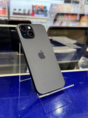 A gray Apple iPhone shown from the back, resting on a clear display stand on a blue counter inside a store.
