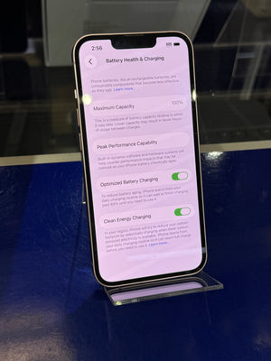 Smartphone displaying battery health and charging information on a reflective surface