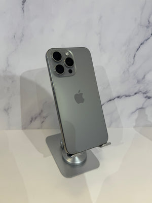 A gray Apple iPhone Pro back view displayed on a metallic stand against a white marble-patterned background.