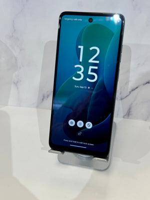 A black smartphone displayed upright on a clear stand against a white marble-patterned background. The screen is on and showing the lock screen with the time 12:35.