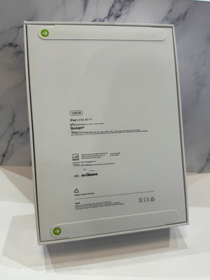 The back of a white Apple iPad box, showing product specifications and recycling information, displayed on a white surface against a marble-patterned background.