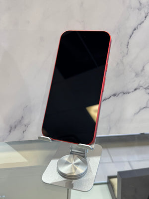 A red smartphone with a black screen stands upright on a silver metal display stand against a white marble-patterned background.