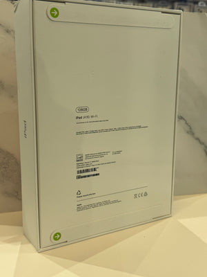 The back of a white Apple iPad packaging box, showing model text 'iPad (A14) Wi-Fi' and regulatory markings, set against a marble-patterned background.