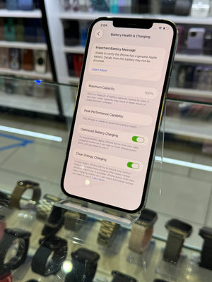 Smartphone displaying battery health and charging information on a glass display stand.