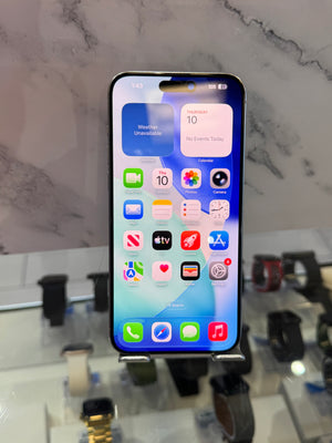 A black iPhone with a lit home screen displaying various colorful app icons, standing on a display stand in a watch and phone store.