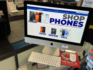 Computer monitor displaying a phone shopping website with a keyboard and mouse on a desk.