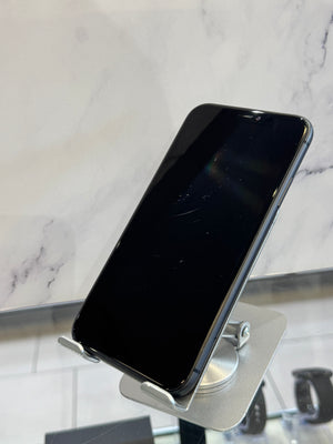 A black smartphone with a glossy screen, resting on a silver metal display stand against a white marble-patterned background.