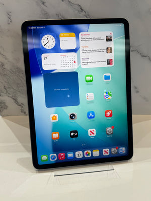 An iPad standing upright on a clear display stand against a white marble-patterned background.