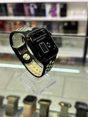 Black smartwatch with yellow accents on a clear stand in a store setting