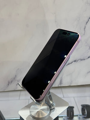 A black smartphone with a metallic rose gold or pink bumper edge, displayed on a silver metal stand against a white marble-patterned background.