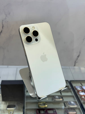 A silver Apple iPhone Pro showing the back of the device with its triple-camera system, displayed on a stand in a retail setting.