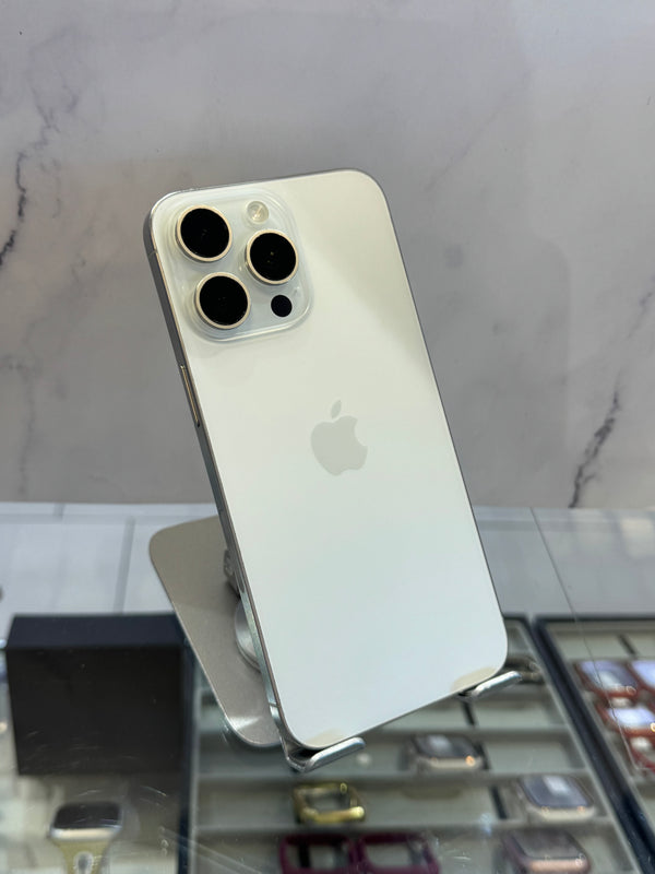 A silver Apple iPhone Pro showing the back of the device with its triple-camera system, displayed on a stand in a retail setting.
