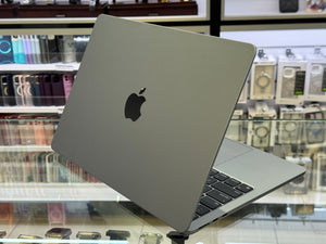 Gray laptop with Apple logo on a glass surface in a store setting