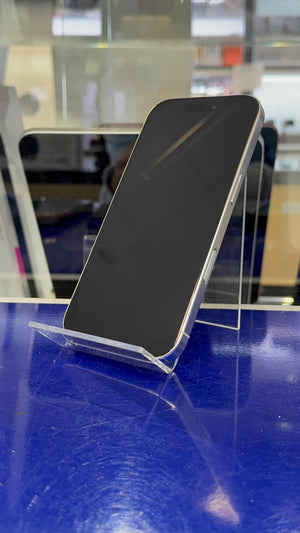 A smartphone with a silver edge, displayed on a clear acrylic stand on a reflective blue surface.