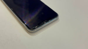 A close-up shot of a smartphone with a black screen and a clear protective case, resting on a plain light surface.