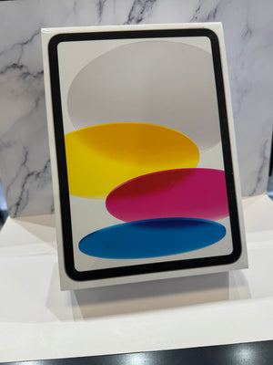 A white rectangular box or case standing upright on a white surface, featuring a black border and an abstract graphic with overlapping yellow, pink, and blue oval shapes on a white background. A gray marble-patterned wall is behind it.