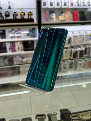 A holographic green and blue Honor smartphone standing on a clear acrylic display stand inside a retail store.