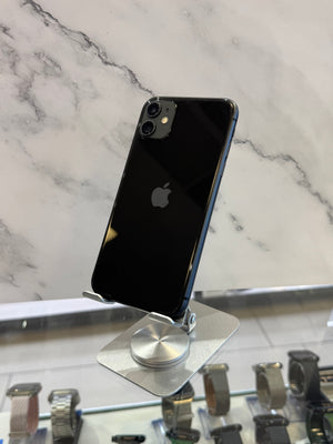 A black Apple iPhone with a gray bumper edge, displayed on a silver stand on a white marble-patterned surface.